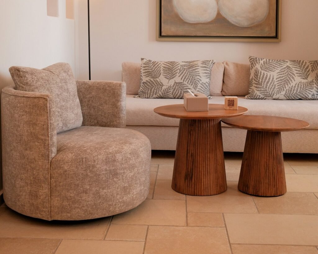 Warm lounge with a curved armchair, cream sofa and round wooden side tables